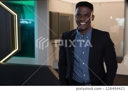 Businessman in modern office smiling confidently, wearing smart suit and blue shirt, copy space 126484421