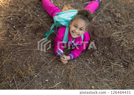 Exploring forest floor, child in pink outfit using magnifying glass, smiling happily, copy space Exploring forest floor, child in pink outfit using magnifying glass, smiling happily, copy space 126484431