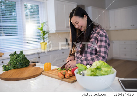 Smiling woman chopping vegetables in modern kitchen, enjoying cooking at home, copy space Smiling woman chopping vegetables in modern kitchen, enjoying cooking at home, copy space 126484439