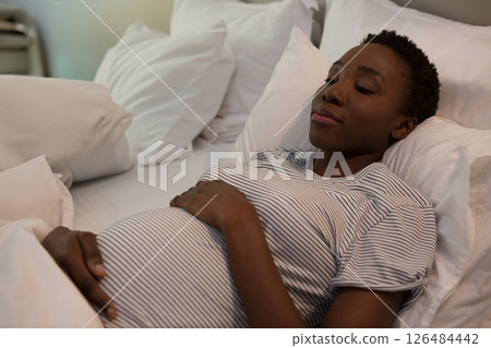 Pregnant woman resting on bed, peacefully holding belly, feeling relaxed at home, copy space Pregnant woman resting on bed, peacefully holding belly, feeling relaxed at home, copy space 126484442