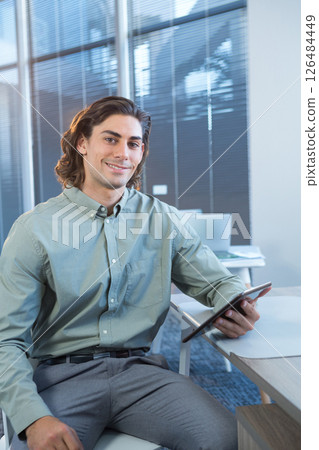 Business professional holding tablet, smiling confidently in modern office setting Business professional holding tablet, smiling confidently in modern office setting 126484449