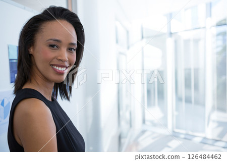 In office, businesswoman wearing elegant black dress, confidently smiling at camera, copy space 126484462