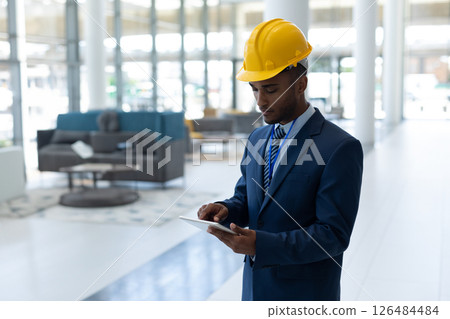 Engineer in suit using tablet in modern office building, focused on work, copy space 126484484