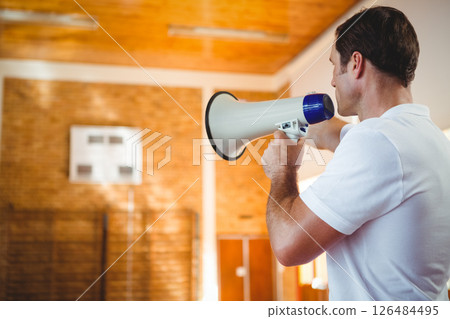 Coach using megaphone in school gym, motivating basketball team during practice, copy space 126484495