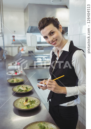 Smiling woman in restaurant taking food order with notepad and pencil, copy space 126484513