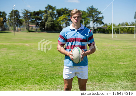 Holding rugby ball, athlete wearing striped jersey on field, looking determined, copy space Holding rugby ball, athlete wearing striped jersey on field, looking determined, copy space 126484519