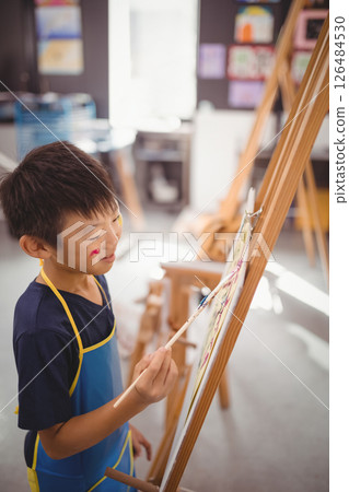 Asian boy painting on easel in art class, enjoying creative activity at school, copy space 126484530