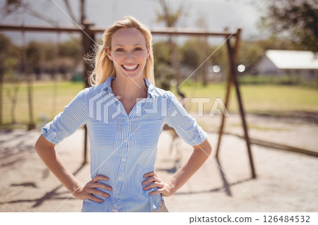 Smiling teacher standing confidently on playground, enjoying sunny day at school Smiling teacher standing confidently on playground, enjoying sunny day at school 126484532