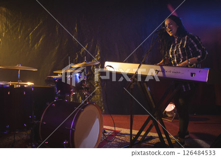 Musician passionately singing and playing keyboard on stage during live performance, copy space Musician passionately singing and playing keyboard on stage during live performance, copy space 126484533