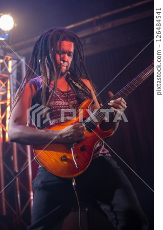 Playing electric guitar on stage, musician performing passionately at live concert 126484541