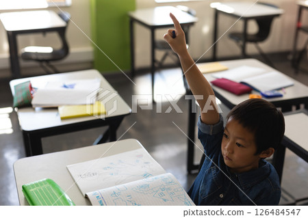 In school, young boy raising hand in classroom, eager to answer question, copy space In school, young boy raising hand in classroom, eager to answer question, copy space 126484547