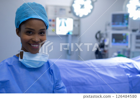 Smiling nurse in surgical scrubs standing confidently in operating room, copy space 126484580
