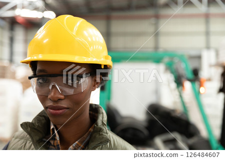 Wearing safety helmet and goggles, warehouse worker confidently standing by forklift, copy space Wearing safety helmet and goggles, warehouse worker confidently standing by forklift, copy space 126484607