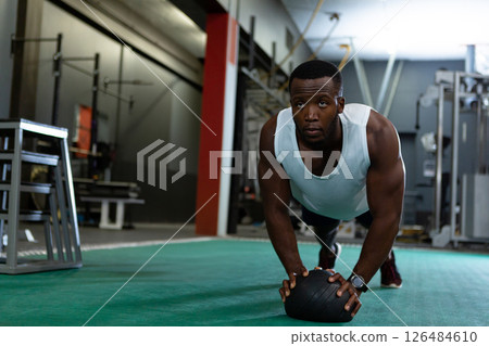Athletic man doing plank exercise with medicine ball in modern gym, copy space 126484610