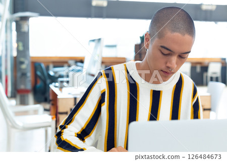 Young man concentrating on laptop work in modern office environment, copy space Young man concentrating on laptop work in modern office environment, copy space 126484673