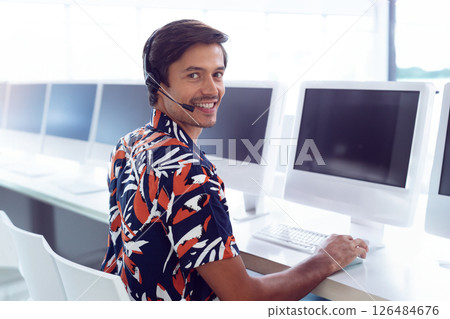 Customer service representative smiling while using headset at computer in office, copy space 126484676