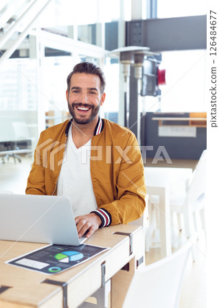 Smiling man using laptop at office, working on project with confidence 126484677