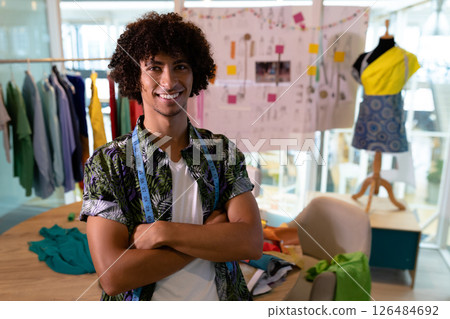 Fashion designer smiling confidently in creative studio with clothing and sketches, copy space 126484692
