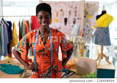 In studio, fashion designer smiling with colorful fabrics and vibrant sketches around, copy space In studio, fashion designer smiling with colorful fabrics and vibrant sketches around, copy space 126484694