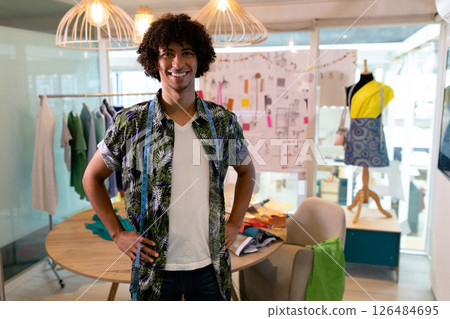 In studio, fashion designer smiling with colorful fabrics and sketches around, copy space In studio, fashion designer smiling with colorful fabrics and sketches around, copy space 126484695