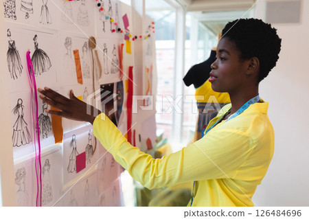 Fashion designer reviewing sketches on inspiration board in modern studio, copy space Fashion designer reviewing sketches on inspiration board in modern studio, copy space 126484696