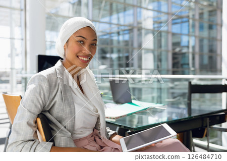 Holding tablet, businesswoman smiling confidently in modern conference room, copy space 126484710