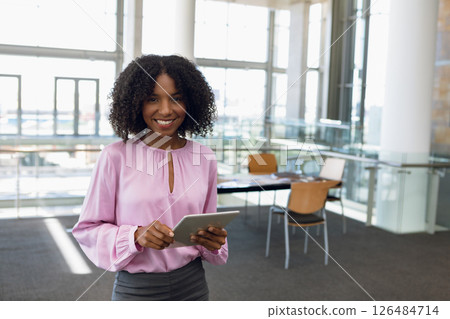 Smiling woman using tablet in modern conference center, standing confidently, copy space Smiling woman using tablet in modern conference center, standing confidently, copy space 126484714
