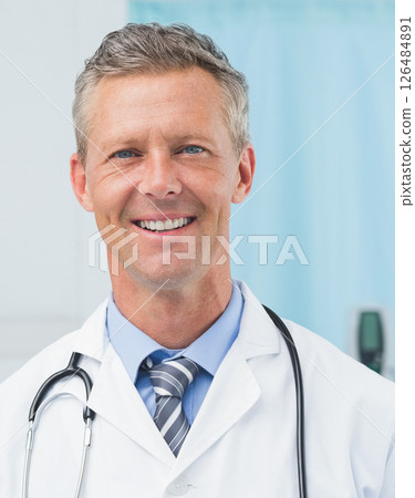 Smiling doctor in white coat with stethoscope in medical office 126484891