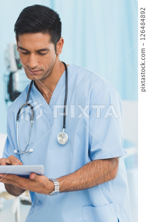 Medical professional in scrubs using digital tablet in hospital setting 126484892