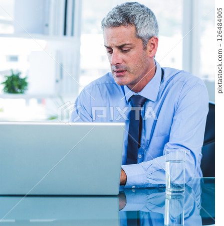 In office, businessman working on laptop, focused and professional at desk In office, businessman working on laptop, focused and professional at desk 126484905
