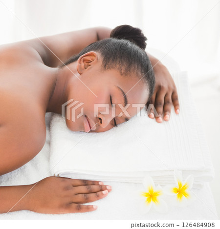 Woman relaxing on spa bed with flowers, enjoying peaceful moment 126484908
