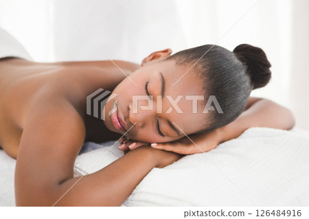 Relaxing at spa, serene woman enjoying peaceful massage on soft towel 126484916