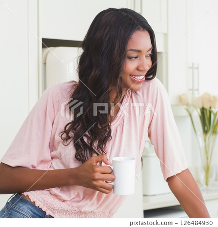 Smiling woman enjoying morning coffee in bright kitchen at home Smiling woman enjoying morning coffee in bright kitchen at home 126484930