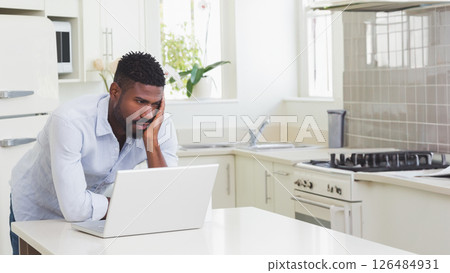 Man working on laptop in kitchen, focusing on task at home, copy space Man working on laptop in kitchen, focusing on task at home, copy space 126484931