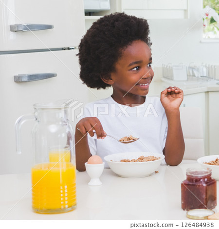 Smiling child enjoying breakfast with cereal and orange juice at home 126484938