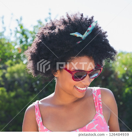Smiling woman wearing sunglasses enjoying sunny day outdoors in summer dress Smiling woman wearing sunglasses enjoying sunny day outdoors in summer dress 126484939