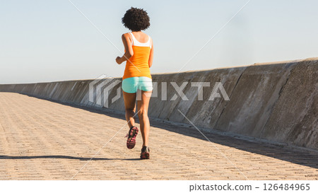 Woman jogging on sunny promenade, embracing fitness and healthy lifestyle 126484965