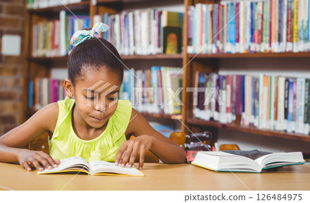Young girl reading book in school library, concentrating on story, copy space 126484975