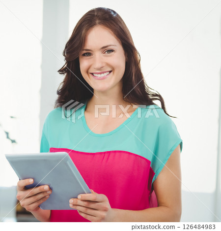 Holding tablet, woman working in modern office environment, smiling confidently 126484983