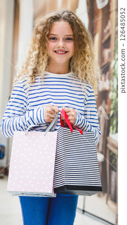 Smiling girl holding shopping bags in mall, enjoying successful shopping day 126485052