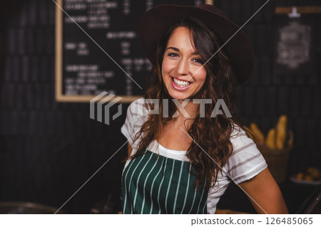 Smiling barista in striped apron welcoming customers at cozy coffee shop 126485065