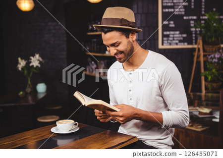 Man enjoying book while sipping coffee in cozy cafe, feeling relaxed 126485071