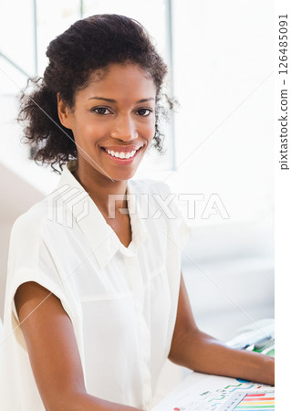 Smiling woman at home reviewing colorful documents, feeling confident and happy 126485091