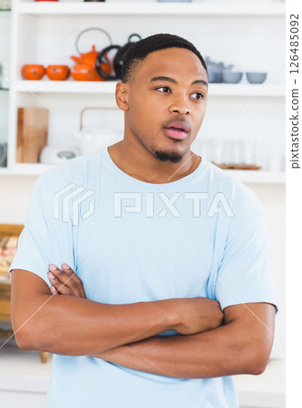 Thoughtful young man standing in kitchen with arms crossed, looking away Thoughtful young man standing in kitchen with arms crossed, looking away 126485092