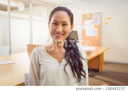 In office, Asian woman embracing casual business environment, smiling confidently 126485137