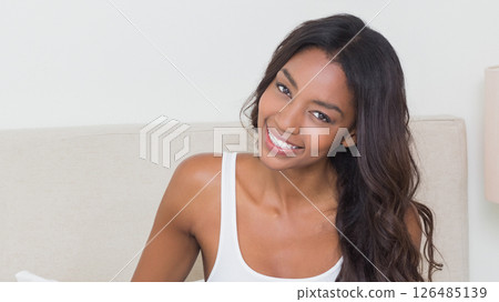 Smiling African American woman relaxing on bed at home, looking cheerful 126485139