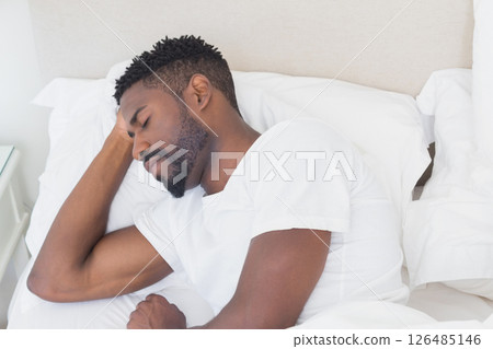 Resting peacefully, man sleeping comfortably in bed at home with cozy blanket Resting peacefully, man sleeping comfortably in bed at home with cozy blanket 126485146