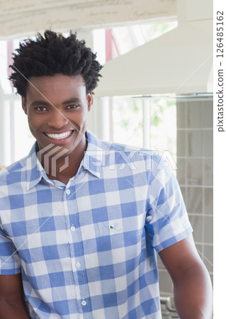 Smiling African American man in kitchen wearing blue checkered shirt 126485162