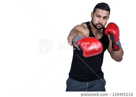 Boxer in red gloves throwing punch, focused and determined in studio, copy space 126485218
