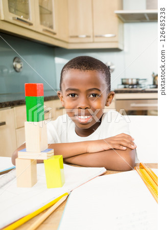 Smiling African American boy playing with colorful blocks at home kitchen table Smiling African American boy playing with colorful blocks at home kitchen table 126485238